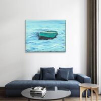Image shows a framed canvas print of green dory adrift in a blue ocean with a blue sky hanging on a wall with a sofa and small table in front of the sofa.